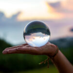 mano-joven-mago-sosteniendo-bola-cristal-hacer-malabarismos-al-atardecer